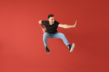 Fototapeta na wymiar Handsome jumping young man against color background