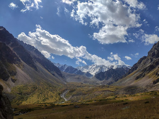 Trans-Ili Alatau mountain range of the Tien Shan system in Kazakhstan near the city of Almaty. Rocky peaks covered with snow and glaciers in the middle of summer under clouds