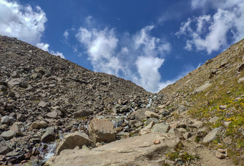 Trans-Ili Alatau mountain range of the Tien Shan system in Kazakhstan near the city of Almaty. Rocky peaks covered with snow and glaciers in the middle of summer under clouds
