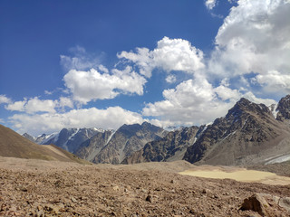 Trans-Ili Alatau mountain range of the Tien Shan system in Kazakhstan near the city of Almaty. Rocky peaks covered with snow and glaciers in the middle of summer under clouds