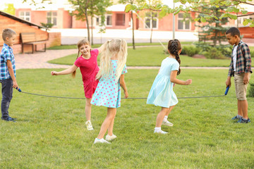 Obraz premium Cute little children jumping rope in park