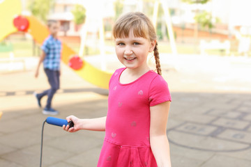 Cute little girl with jumping rope on playground