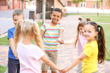 Cute little children doing circle dance outdoors