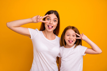 Portrait of two nice attractive lovely comic crazy childish cheerful cheery glad positive person showing v-sign having fun fooling isolated over bright vivid shine yellow background