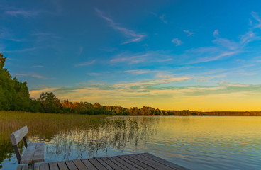 Summer evening on Lake Seliger. Beautiful sunset sky is reflected in the water. Thickets of reeds in the foreground. On the far shore is a forest. Rest and relaxation.