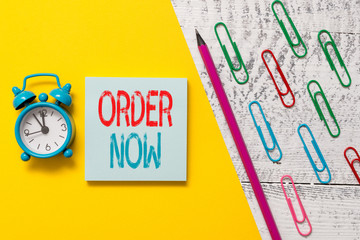 Handwriting text Order Now. Conceptual photo the activity of asking for goods or services from a company Notepad marker pen colored paper sheet clips alarm clock wooden background