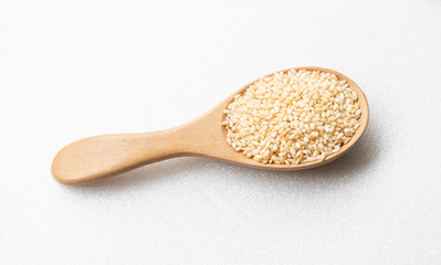 white sesame seeds on wooden spoon isolated on white background