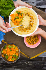 Original homemade arabic chickpea hummus with olive oil and cumin. Creamy dip paste. Adult woman and child, kid hands have food together. Family lunch.