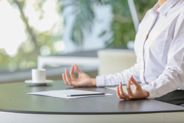 Young businesswoman meditating at workplace in office