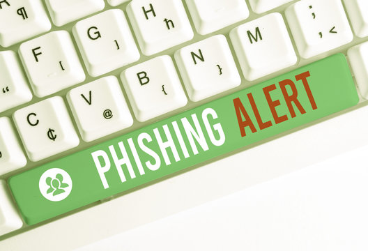 Writing note showing Phishing Alert. Business concept for aware to fraudulent attempt to obtain sensitive information White pc keyboard with note paper above the white background