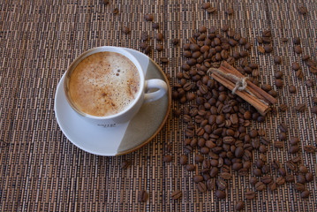 cup of coffee coffee beans cinnamon on a brown background