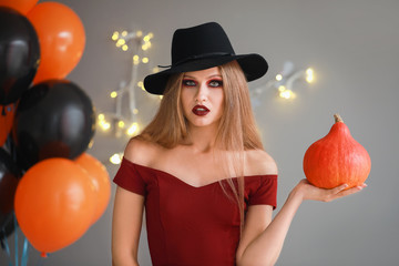 Beautiful woman dressed as witch for Halloween on grey background