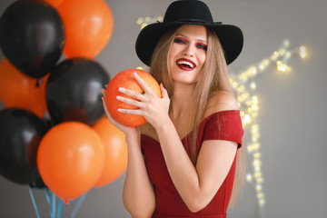 Beautiful woman dressed as witch for Halloween on grey background