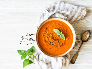 Tomato soup with spices and fresh basil on a white wooden background. Top view. Copy space