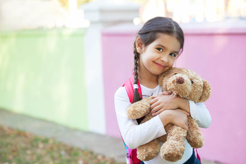 Adorable little child girl with a teddy bear outdoors. School time. 