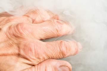 Hand of a man in the white smoke from the fire