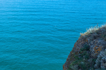 Part of a huge colored rock against the background of the azure colors of the sea. Cape Kaliakra, Black Sea, Bulgaria.