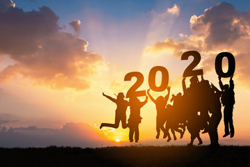 Silhouette of Business teamwork hands up and jump to the beautiful golden sky from text 2020...