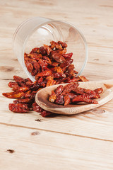 SPICY RED PEPPERS ON WOOD SPOON AND RUSTIC TABLE