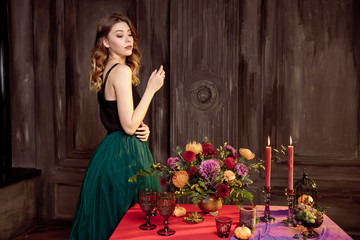Obraz na płótnie Canvas Happy Halloween.Attractive young woman getting ready for Halloween by setting the table for a festive dinner. Beautiful woman pumpkin.