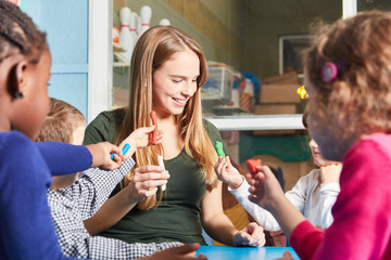 Betreuerin und Kinder spielen mit Knete