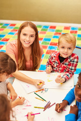 Frau als Erzieher malt zusammen mit Kindern