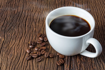 Coffee cup and roasted coffee beans on the old wooden floor.