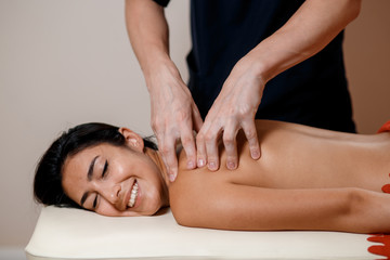 Fototapeta na wymiar A young woman gets a massage procedure. Masseur makes back massage.