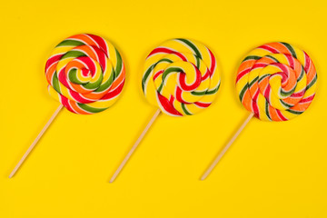 Colorful candy on a yellow  background. Lollipop. Top view. Copy space.