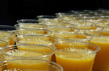 View of plastic glass rows filled with fresh orange juice