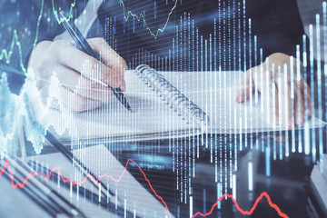 Forex chart hologram on hand taking notes background. Concept of analysis. Multi exposure