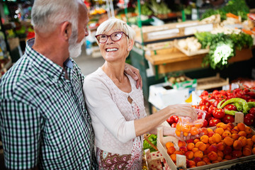 Mature couple shopping vegetables and fruits on the market. Healthy diet.