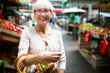 Only the best fruits and vegetables. Beautiful mature woman buying fresh food on market
