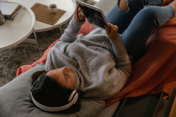 Young brunette woman watching tablet with headphones on