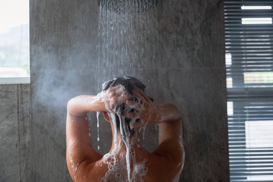 Young woman washing her hair in a shower in a modern bathroom
