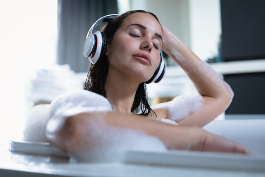 Young brunette woman listening to music in the bath