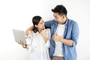 Happy Asian couple using laptop against white wall, lifestyle concept.