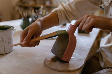 Female potter in a pottery studio painting clay flask