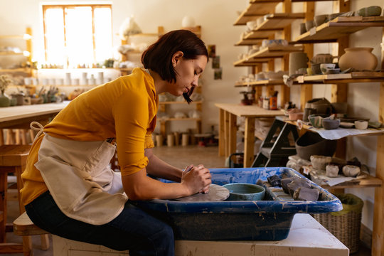Female potter in a pottery studio using pottery wheel