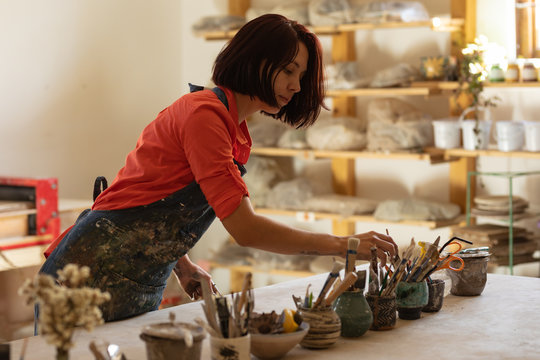 Female potter in a pottery studio choosing tools
