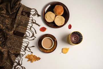 Autumn composition.A Cup of coffee, a candle, a scarf, English muffins, autumn leaves on a white background.