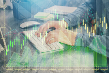 Stock graph with businessman typing on computer in office on background. Concept of analysis. Double exposure.