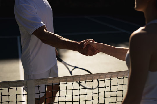 Woman and man shaking hands at a tennis court