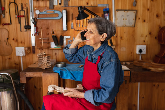 Female luthier talking on the phone in a workshop