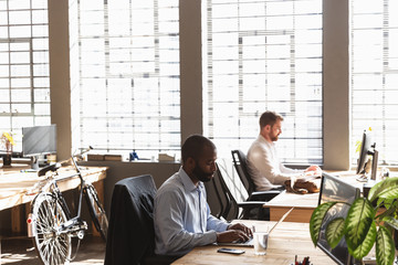 Young creative professional men working in a sunlit office