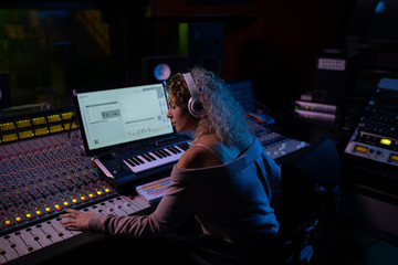 Female music producer working at the mixing desk in a sound studio