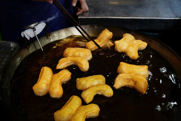 Chef making Youtiao in Hot Frying Pan in Local Market, Traditional Fried Dough Food. Chinese Cruller