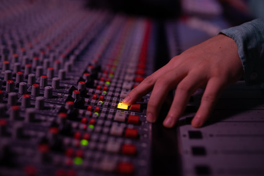 Male music producer working at the mixing desk in a sound studio 