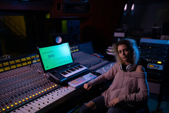 Portrait of female music producer at the mixing desk in a sound studio