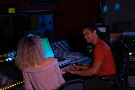 Male and female music producers working together in a sound studio